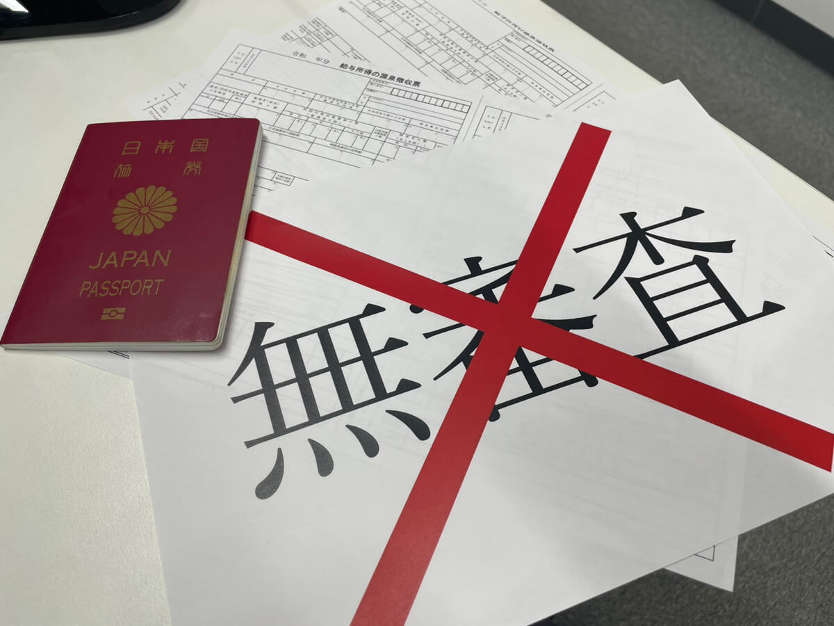 無審査に赤いバツをつけた紙とパスポートの写真