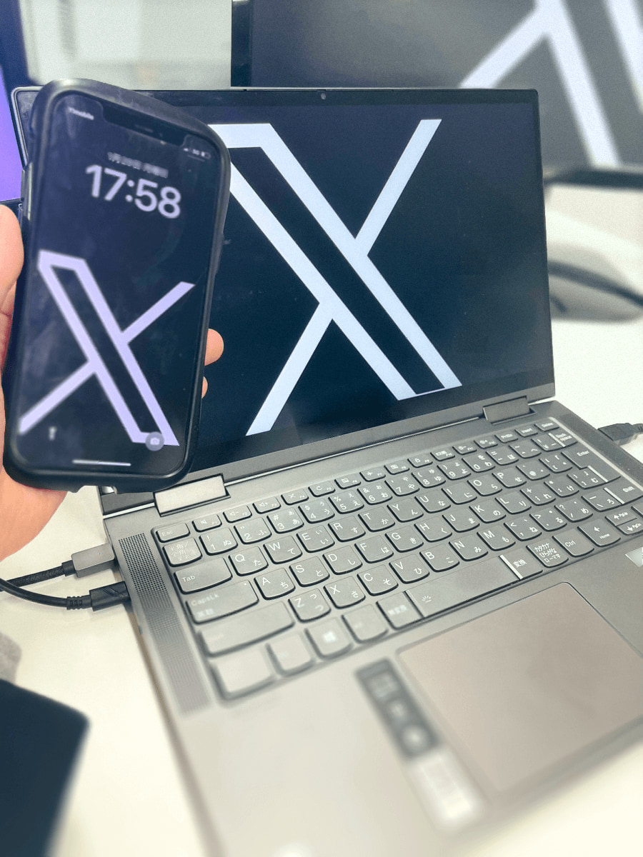 Xのロゴ画面を写したスマートフォンとパソコン