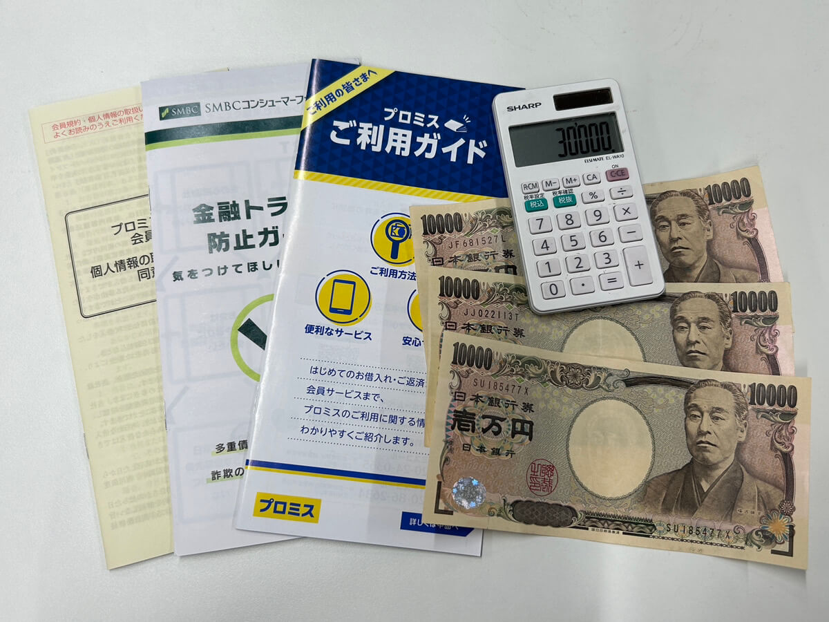 消費者金融のパンフレット3冊と現金3万円と電卓