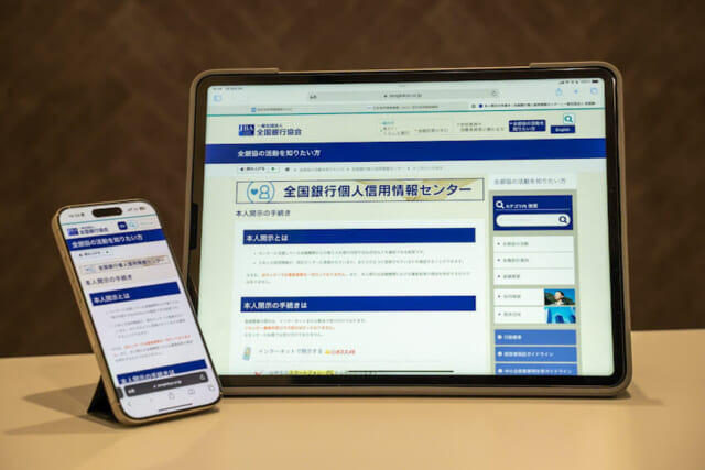 全国銀行個人信用情報センターのWebページを映したスマホとタブレット